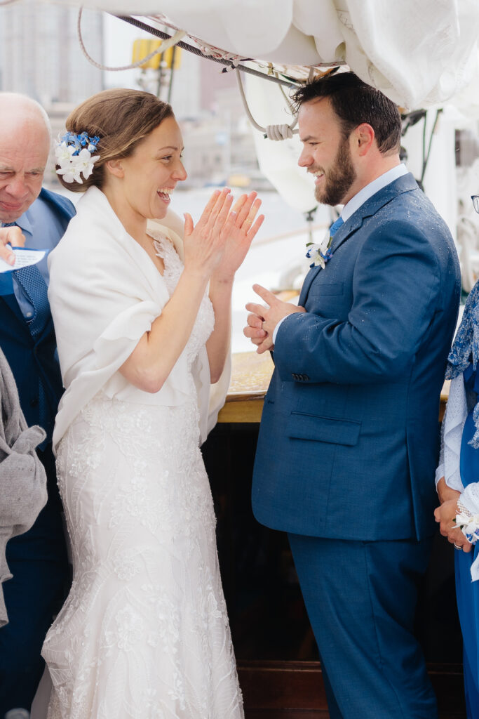Bride and groom sharing joyous moment during wedding ceremony on a boat.