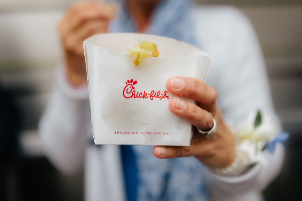 A person holding Chick-fil-A fries pack, with a focus on crispy waffle fries and brand logo.