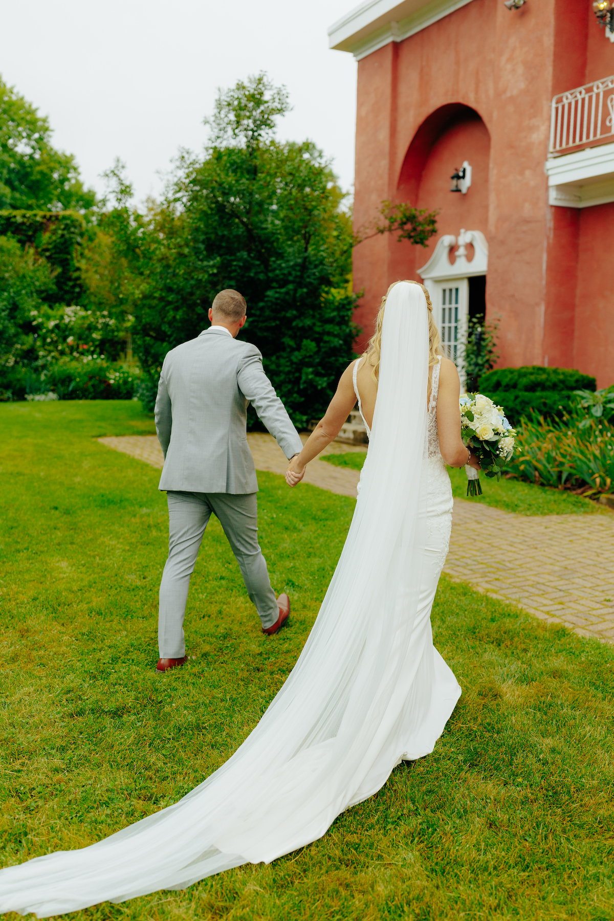 Bride and groom walking hand in hand on a garden path at hidden hills nh, elegant wedding scene.